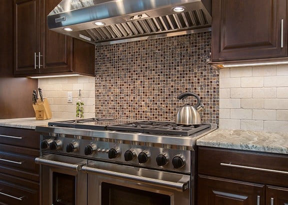 Cherry cabinetry with stainless stove/oven combo and beautiful decorative tile