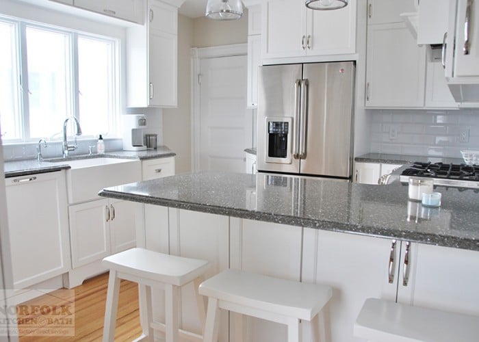 small white kitchen with dark granite countertops and white stools