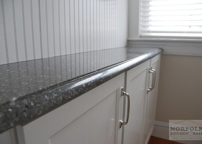side view of countertop edge and white cabinets and stainless pulls