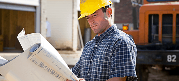 home builder with hard hat examining building plans