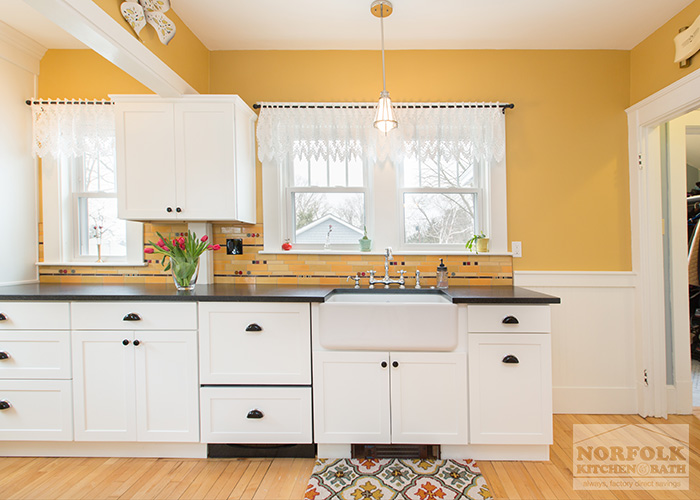 white cabinets with farmers sink and black heat vent at toekick