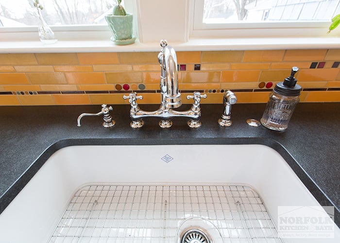 close up of white sink with chrome faucet and sprayer and soap dispenser