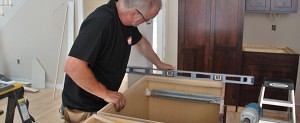 a Norfolk kitchen installer checking to make sure a base cabinet is level during install