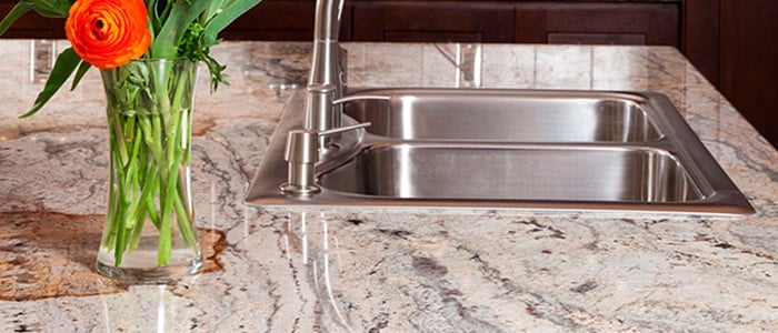 close up of a granite countertop and a stainless steel drop in sink with faucet