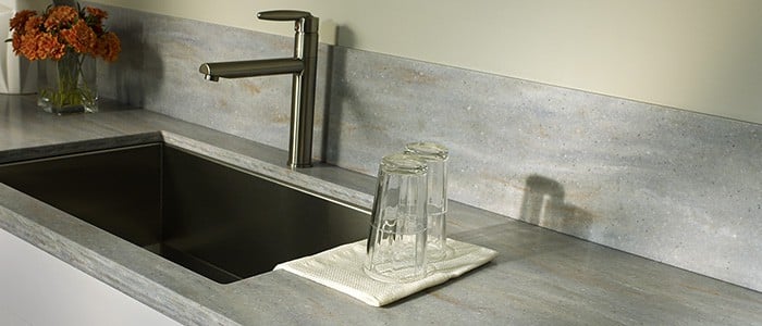 close up of a solid surface countertop with 2 glasses next to a stainless steel sink