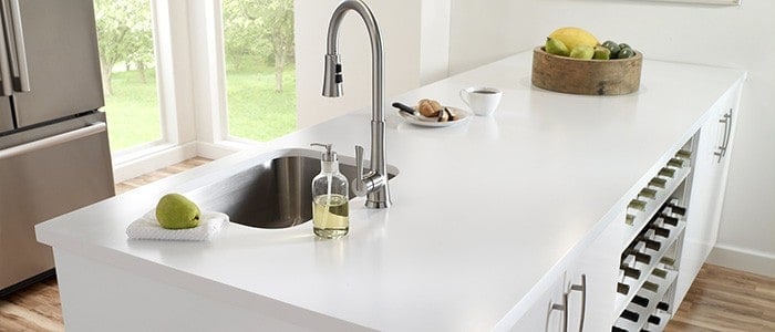 a kitchen island with a solid surface countertop and a stainless steel sink and faucet