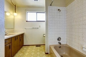 Outdated bathroom with linoleum tile and dark wood cabinets