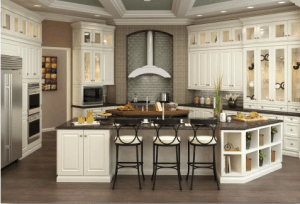 Large white kitchen with oversized white island with shelving and glass doors and shaped stainless hood