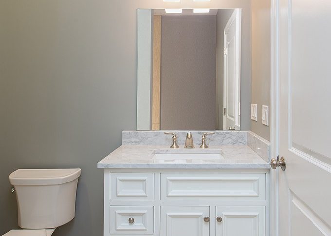 white vanity cabinet with decorative doors mirror and light fixture
