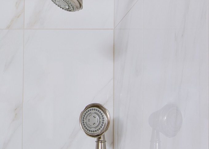 white marble tile in shower showing brushed stainless faucet