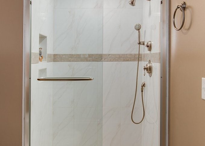 white marble tile full shower with accent tile in brown line