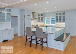Oversized white kitchen island with seating bench and hardwood floors