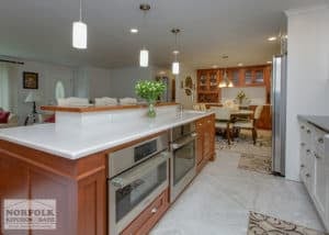 Multi-level kitchen island with cherry tone cabinets and light colored quartz tops