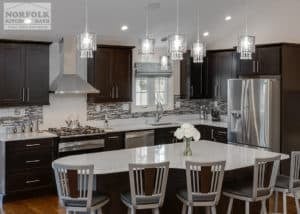 dark finish Custom shaped kitchen island with seating and white quartz countertops and stainless appliances and chairs