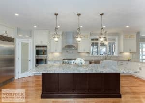 spacious kitchen with island in dark toned wood and grey granite and hardwood floors