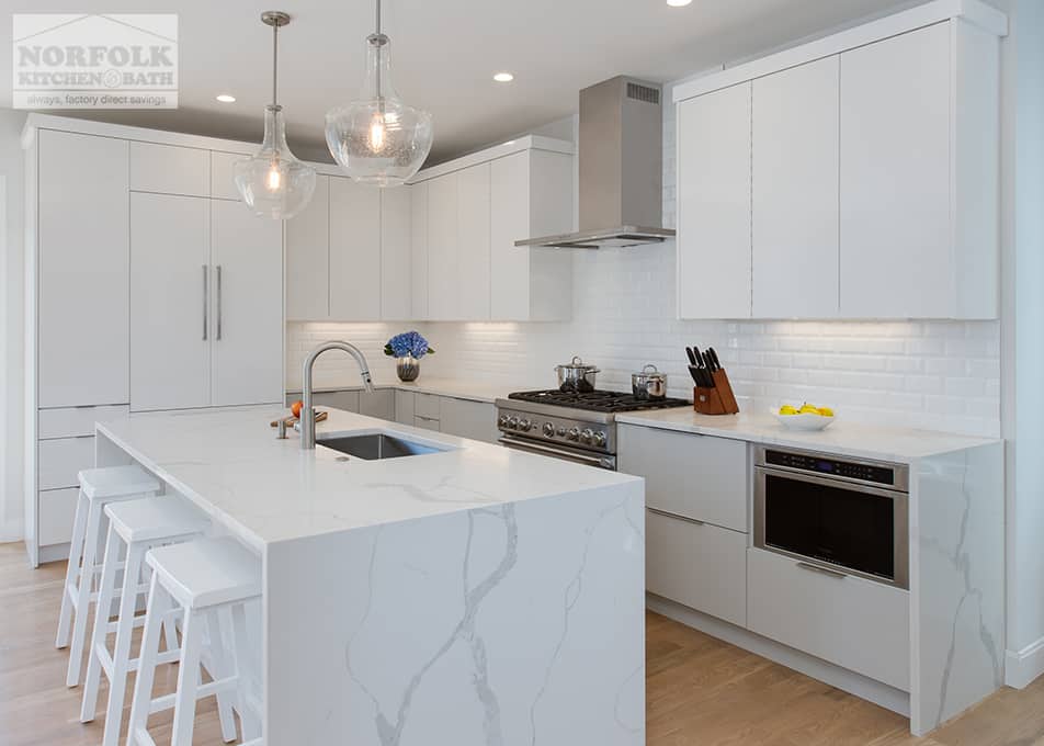 contemporary L-shaped kitchen in Boston with white full-access cabinets, a large island and a marble looking quartz countertop with a waterfall edge
