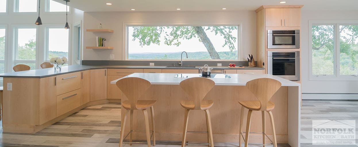 modern full-access kitchen cabinets in a natural finish with a large picture window overlooking trees