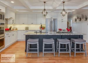 white kitchen with black island and grey stools.