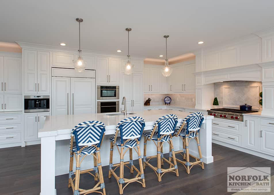 an L-shaped kitchen with a large island, 4 nautical bar stools and pendant lighting over the island