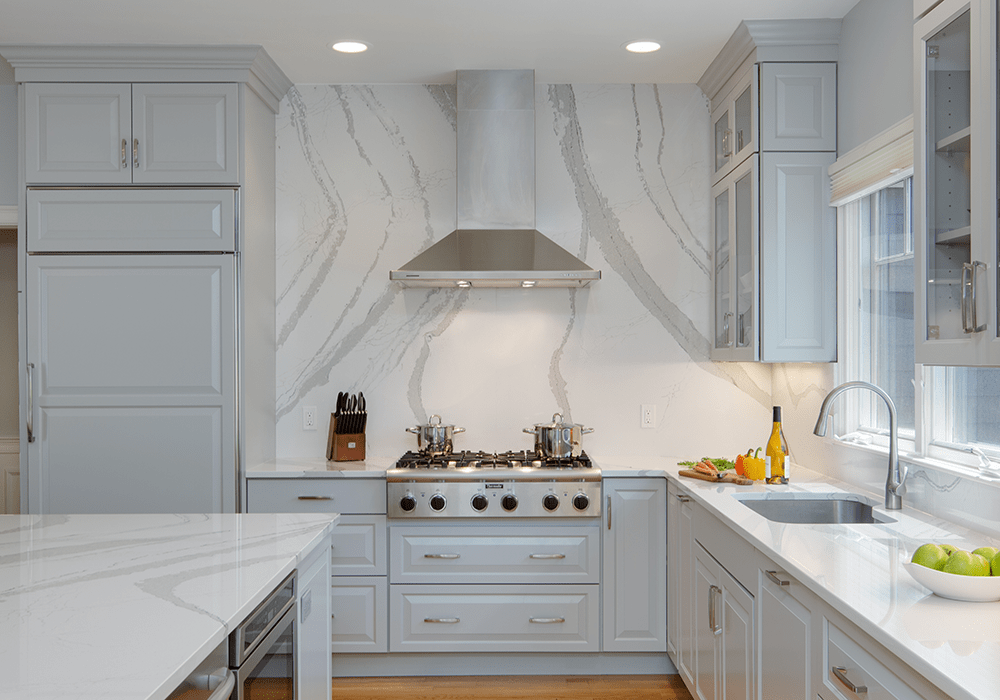 a modern grey kitchen with cambria quartz countertops and a cambria quartz backsplash going all the way to the ceiling