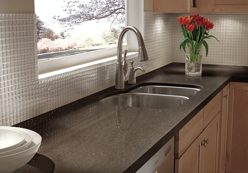 close up of a dark solid surface kitchen countertop with a stainless steel sink and a pull-down faucet