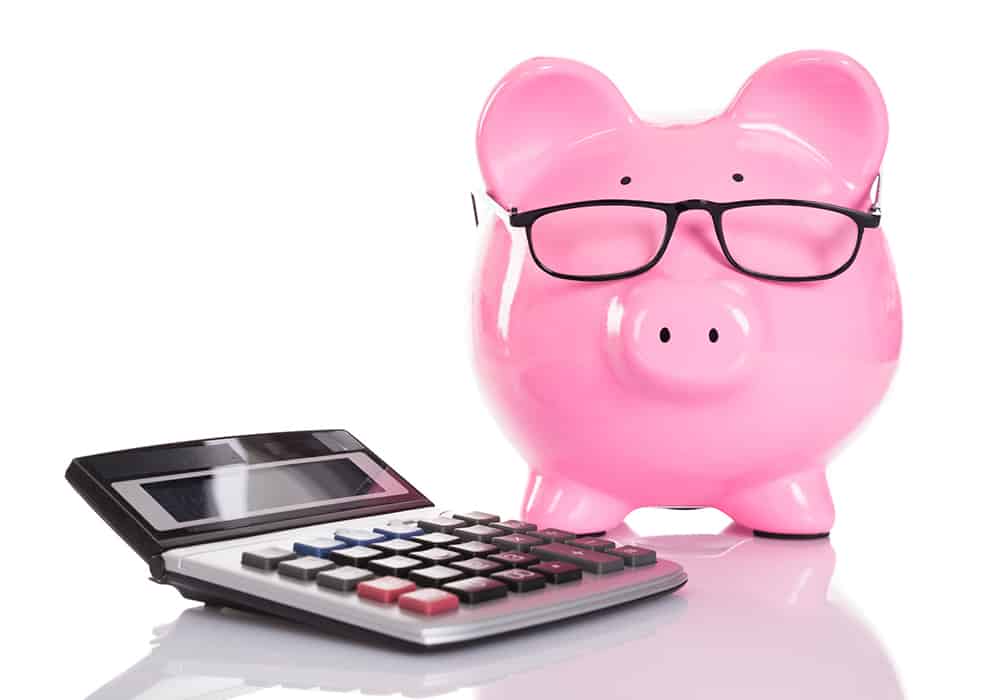 a pink piggy bank with glasses on and a calculator next to it