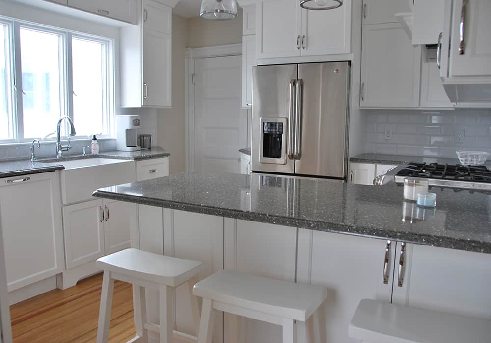 White kitchen with black countertops and white stools in customer home