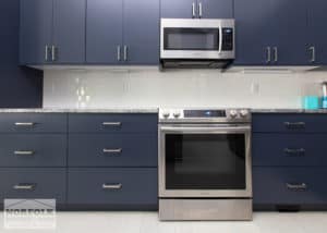 blue kitchen cabinets with kitchen stove and hanging microwave. Colored cabinetry is an up and coming kitchen trend