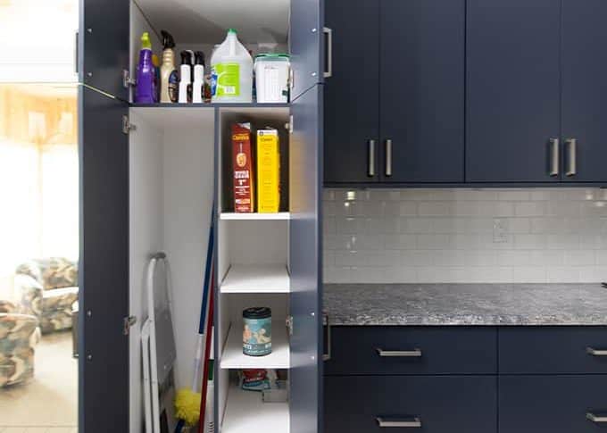 a tall utility cabinet with cleaning supplies in a contemporary blue kitchen