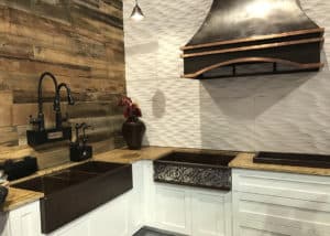 White cabinets with wood tops and reclaimed wood accents and large metal hood