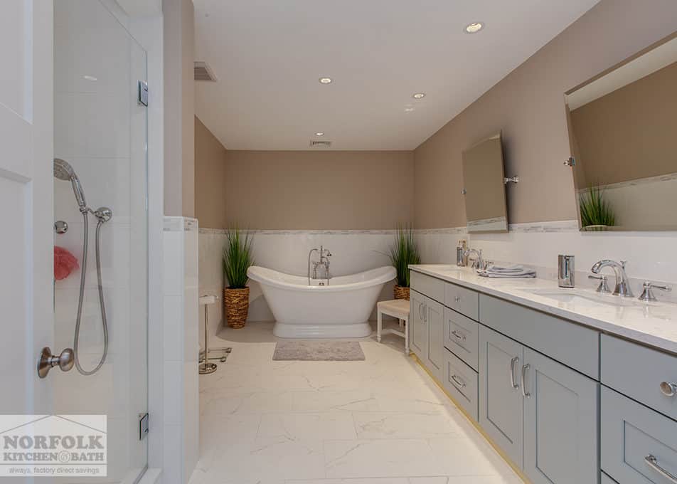 a large master bathroom with a standalone tub at the end and a long double vanity to the right side