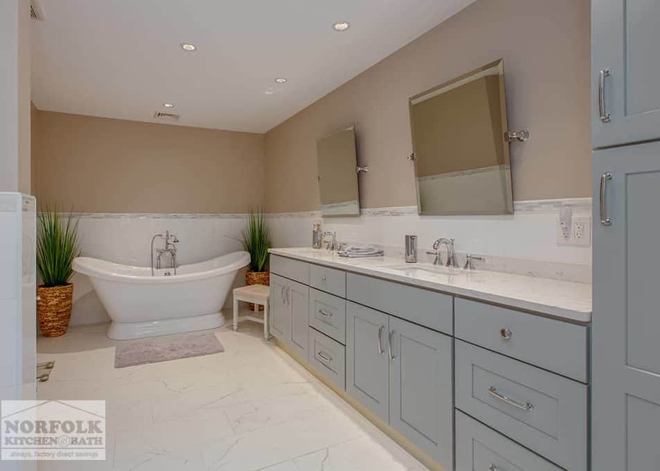 a master bathroom with a large grey vanity with a double sink and a standalone white soaking tub to the left