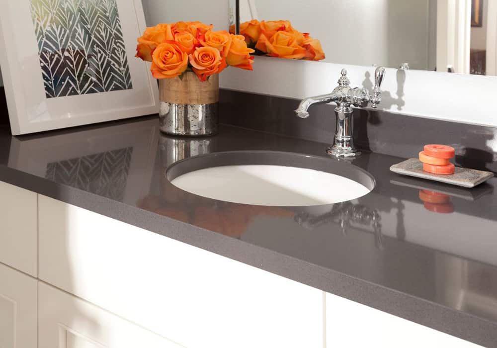 close up of a grey Cambria quartz bathroom vanity top with orange flowers on top