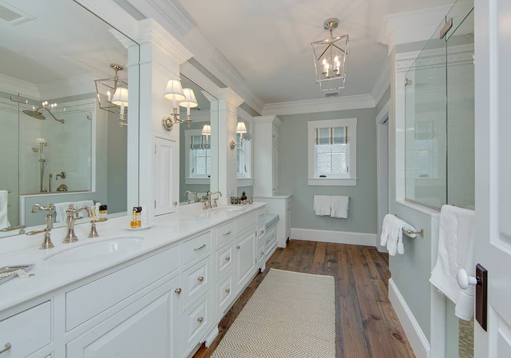 custom bathroom remodel with large white double vanity and a walk in glass enclosed shower and wood flooring