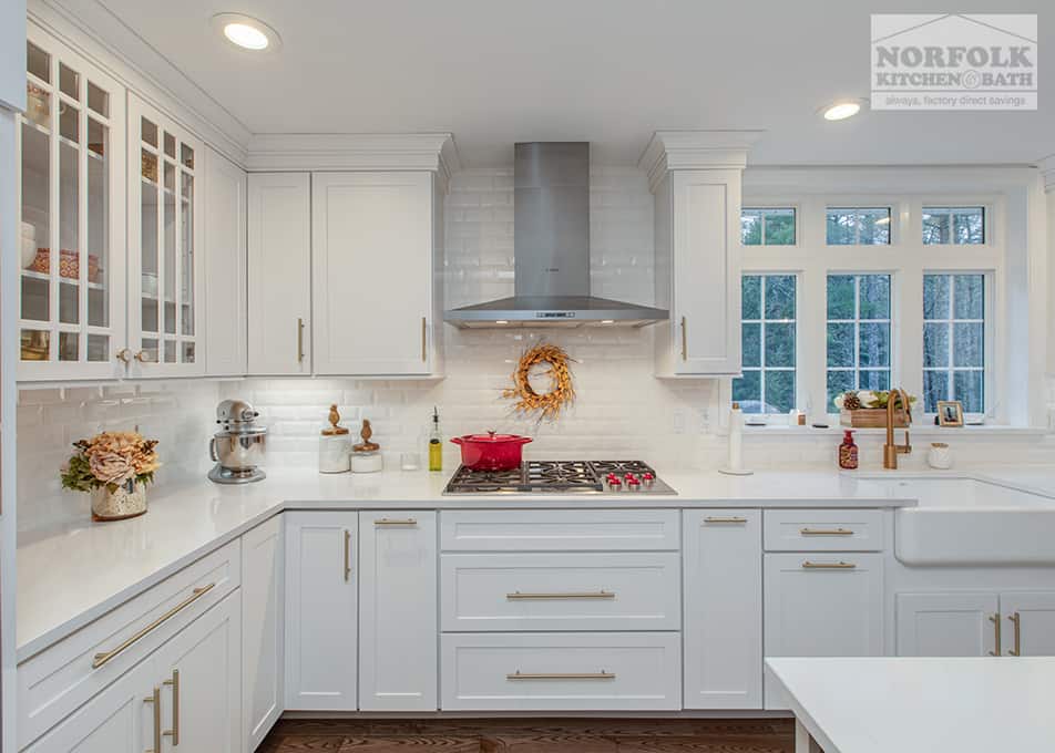 close up of white shaker cabinets with a standalone stainless steel range hood over a gas cooktop