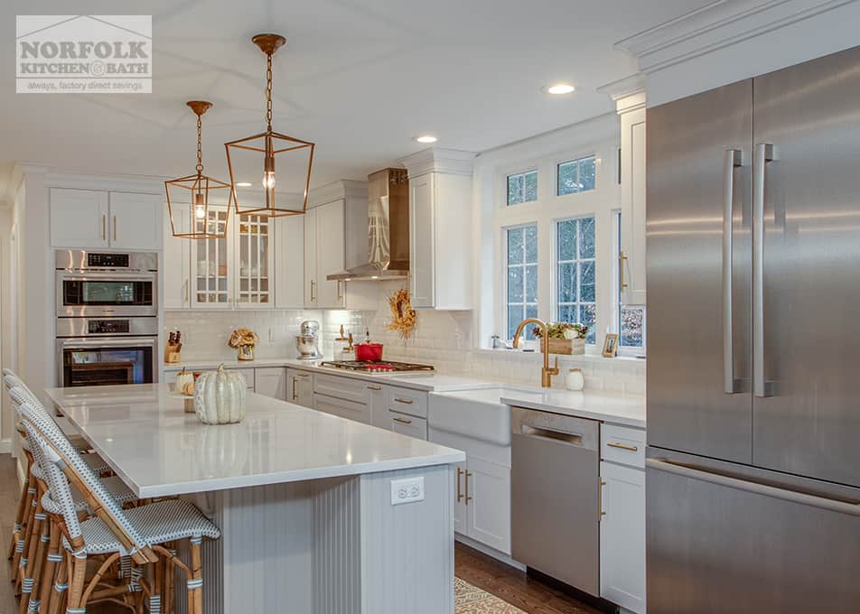 white kitchen with elegant gold finish light fixtures and stainless refrigerator