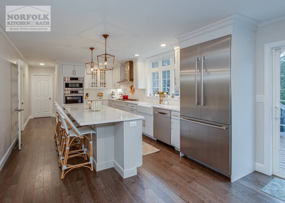 a large white kitchen with an island featuring gold accents and stainless steel appliances