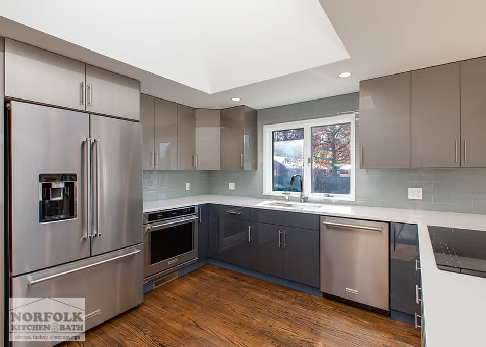 a modern, high-gloss kitchen with gray wall cabinets, blue base cabinets and stainless steel appliances