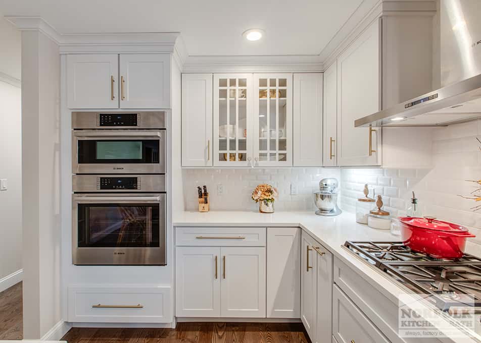 white kitchen cabinets with wall ovens and gold cabinet hardware