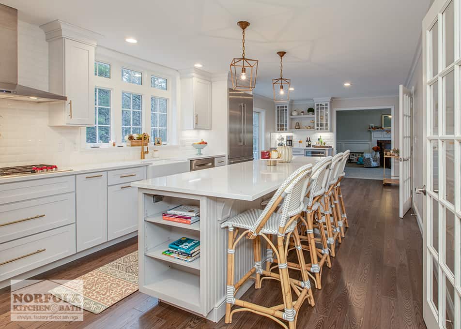 a large white kitchen with island leading into a living room