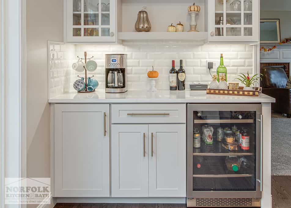 close up of white base cabinets with a beverage cooler, and a coffee maker and wine bottles on the counter