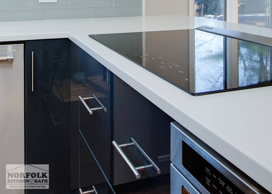 close up of high-gloss blue cabinets and a white quartz countertop with an electric cooktop