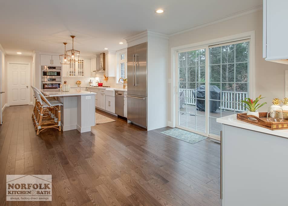 dining area with no table that leads into an updated white kitchen with stainless steel appliances