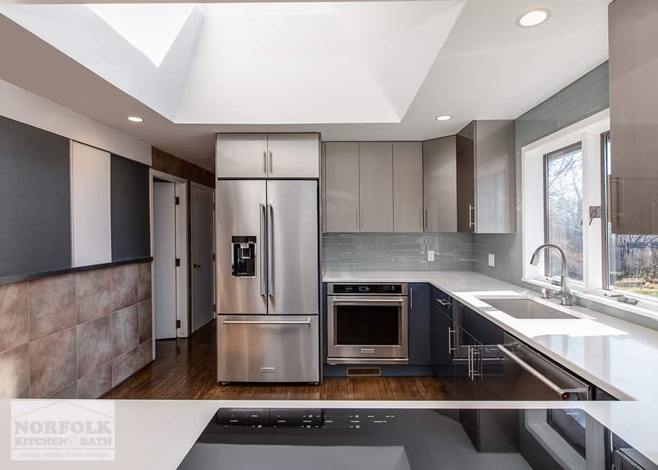 a modern, high-gloss kitchen with gray wall cabinets, blue base cabinets and stainless steel appliances