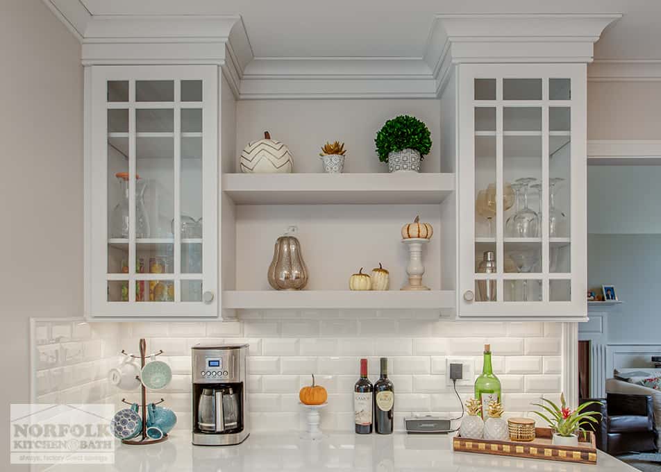 close up of 2 white kitchen cabinets with mullion glass doors and white floating shelves in between them