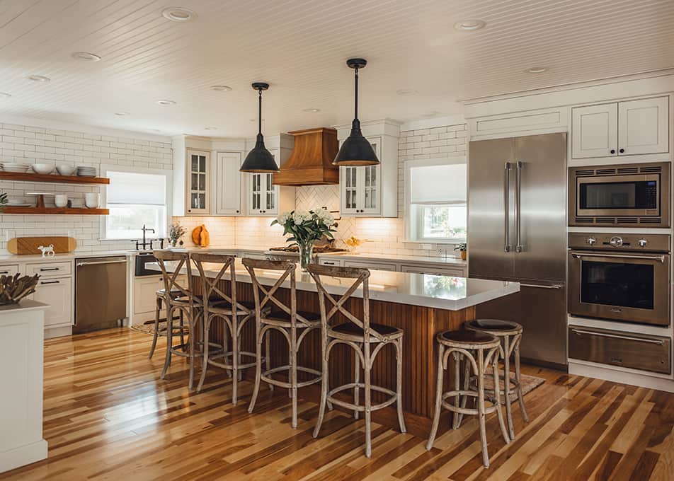 a white L-shaped kitchen with an expansive woodgrain accent island and matching wood range hood