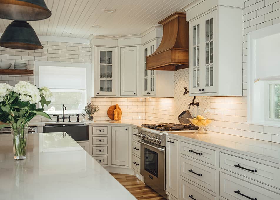 a modern white farmhouse kitchen with a wood accent hood and open shelving