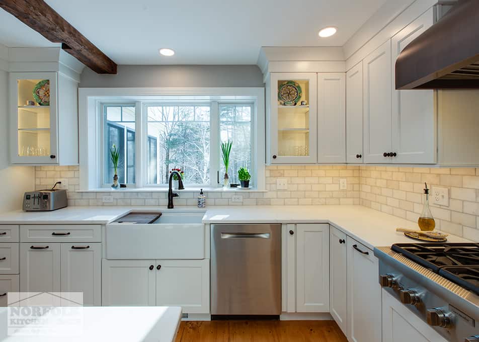 white kitchen cabinets with a stainless steel dishwasher and a white apron sink