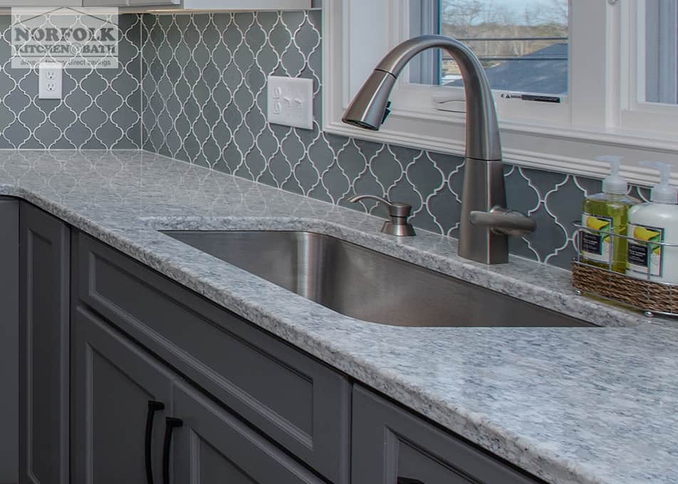 close up of a stainless steel undermount sink, pull down kitchen faucet and a quartz kitchen countertop