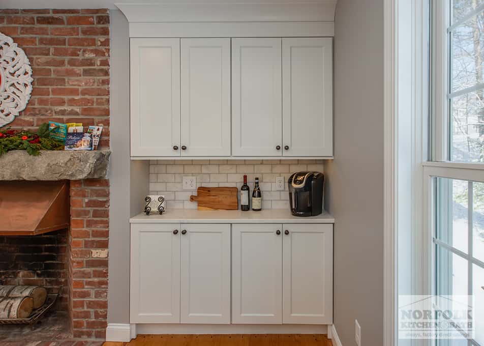 a kitchen beverage station with built-in white cabinets